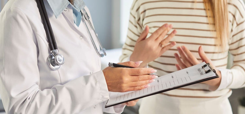 An image of a doctor taking notes, while a patient is explaining their symptoms.
