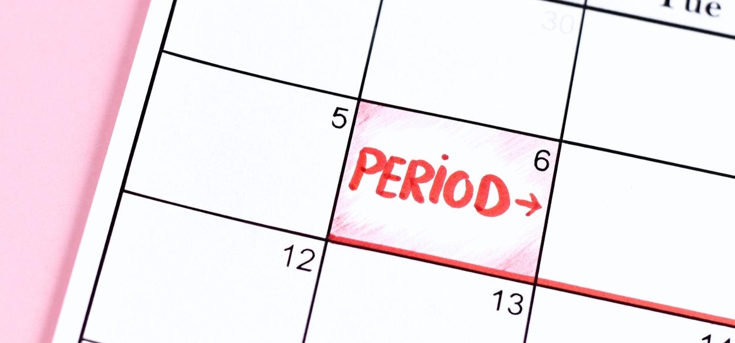 A calendar with the word "PERIOD" and an arrow written in red marker to track a menstrual cycle.