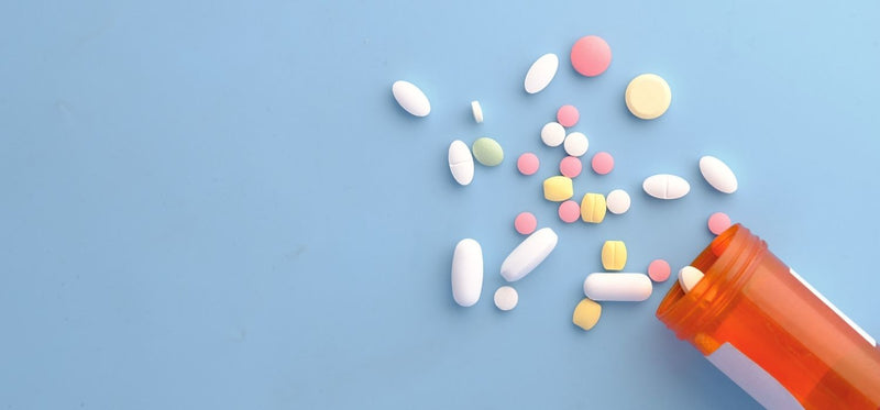 An open medication bottle with scattered pills on a blue background.