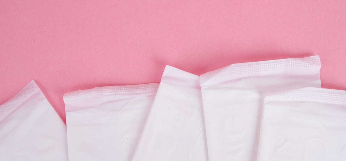 White menstrual pads arranged on a pink background, illustrating vaginal bleeding related to yeast infections.