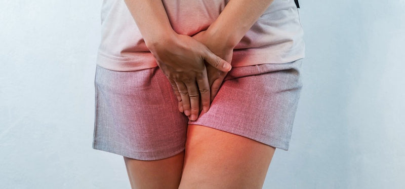 Woman holding hands over pelvic area with red highlighting.