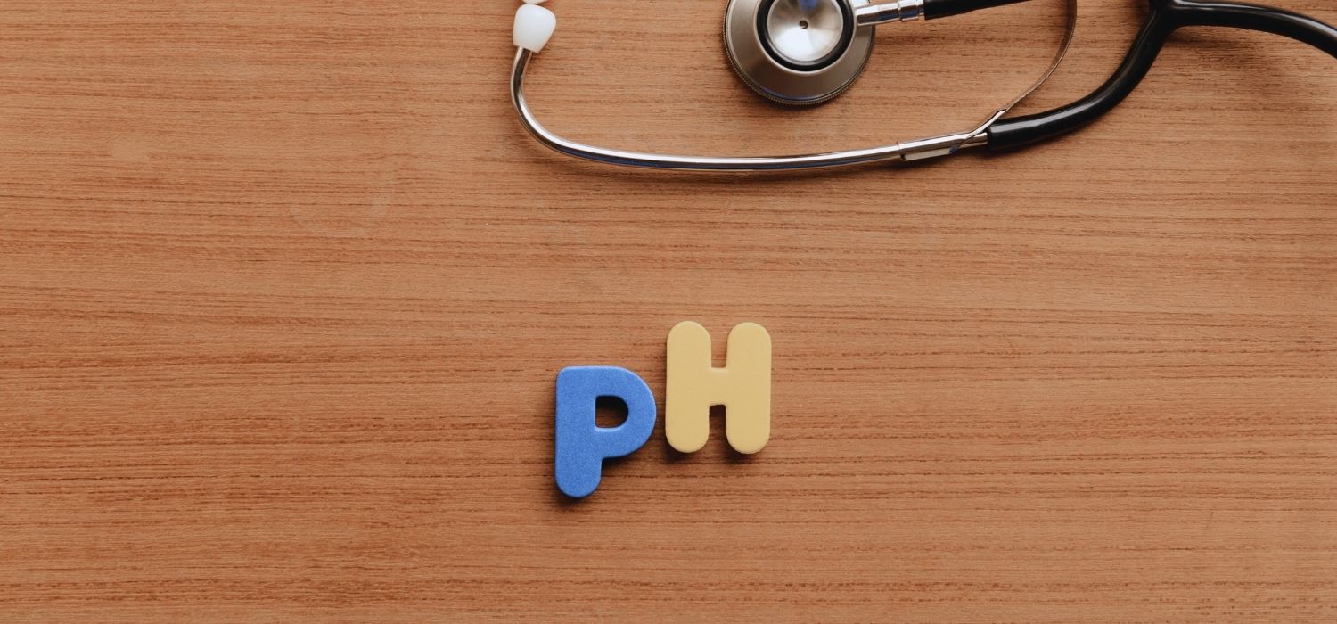 A medical-themed image of the letters "pH" and a stethoscope on a wooden desk.