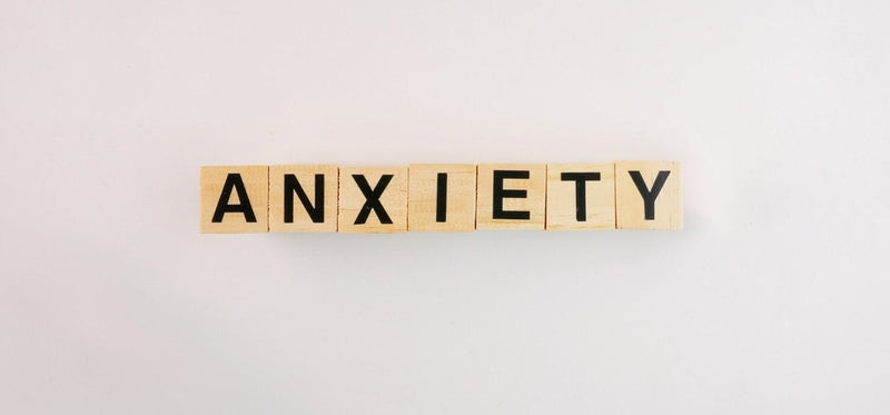 Wooden letter blocks spelling out the word "ANXIETY" centered on a plain white background.