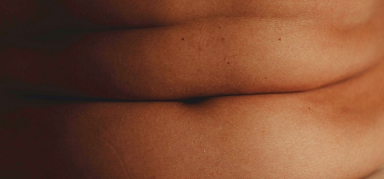 A close-up image of natural stomach rolls and skin texture, illustrating menopausal belly fat.