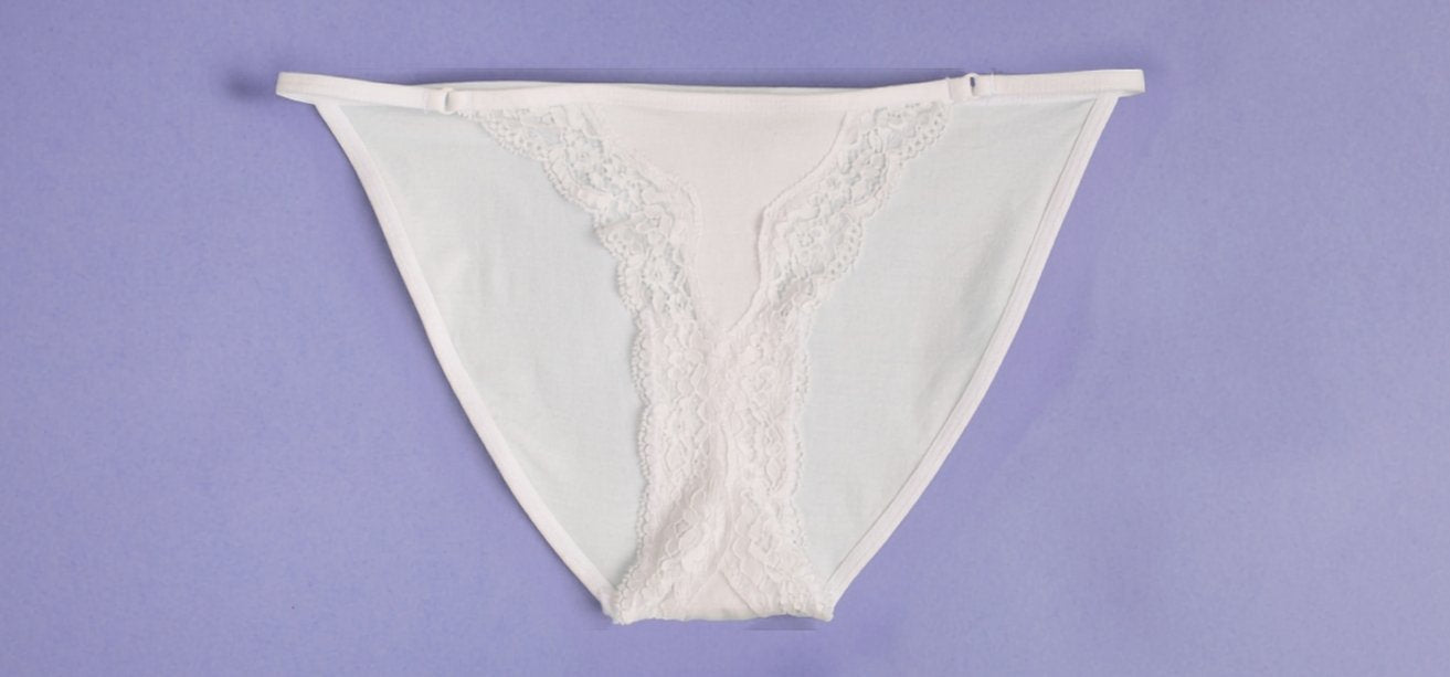 White lace-trimmed underwear laid flat on a solid purple background.