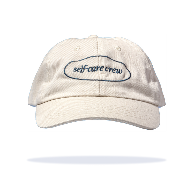 Cream cap with "self-care crew" text, symbolizing Happy V's commitment to women's wellness.