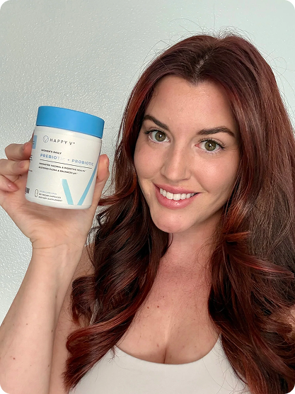 Woman holding a container of Happy V prebiotic and probiotic supplement against a plain background.