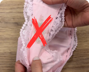 Close-up of pink underwear showing a fabric defect with a visible tear and lace trim.