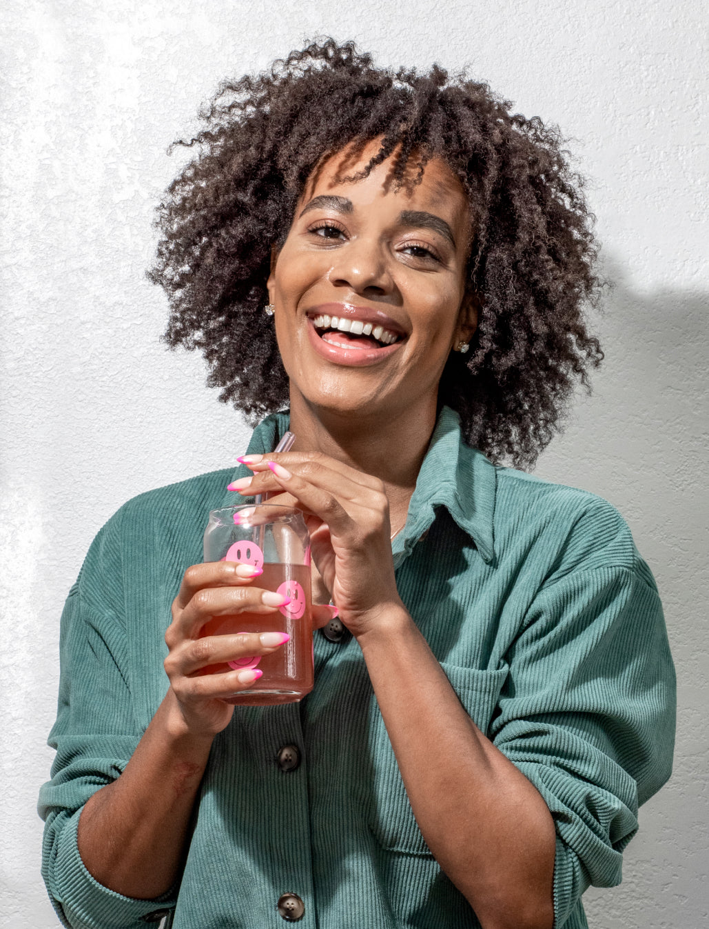 A portrait photo of a woman with curly hair drinking with a glass straw from a Happy V glass blog banner image