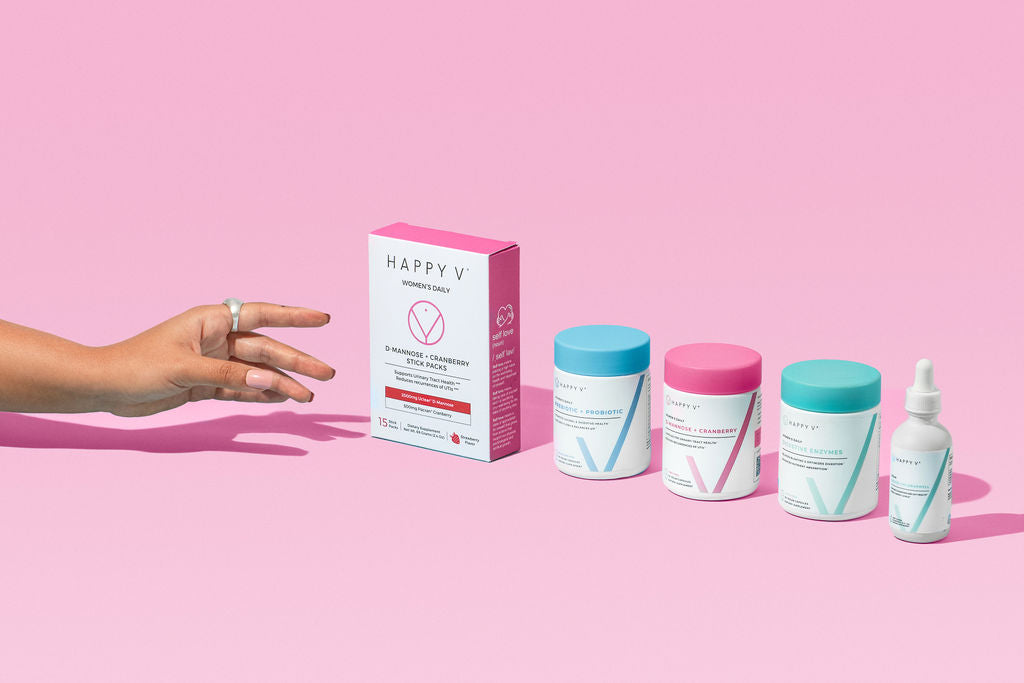 A hand reaching out to a collection of Happy V products on a pink background large image