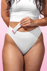 Woman in white holding a Happy V supplement tube for feminine wellness support.