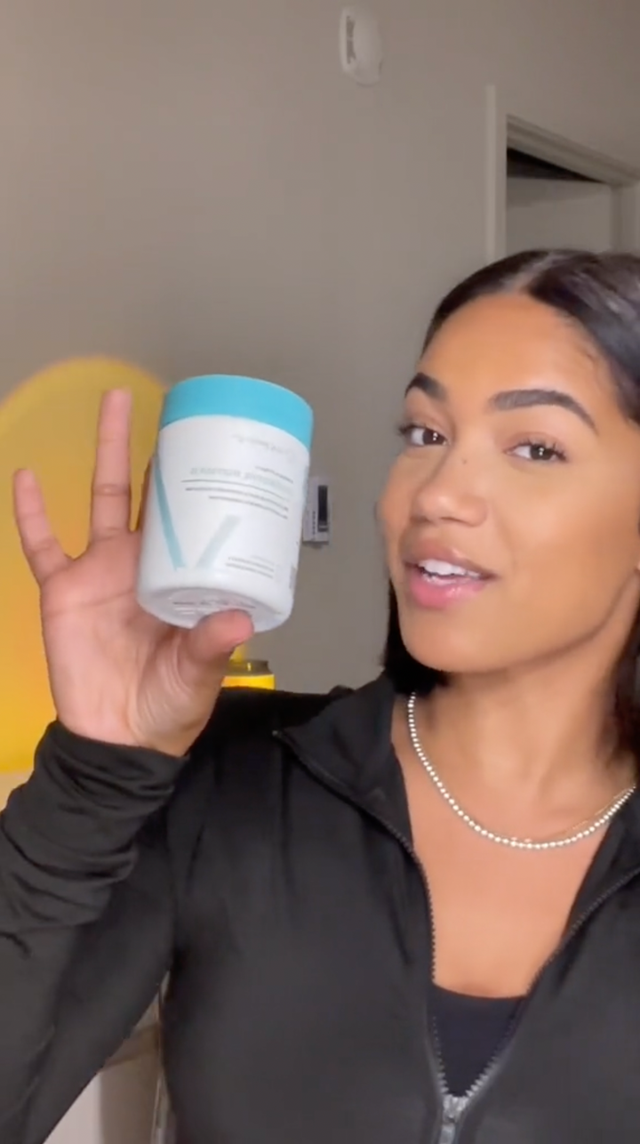 A smiling customer holding a bottle of Happy V Digestive Enzymes next to her face small image