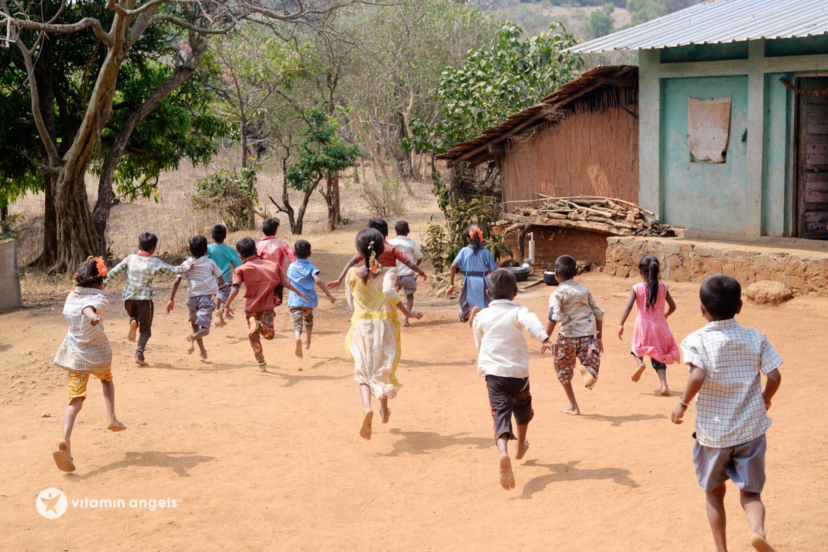 Village children running away from the camera, part of the Vitamin Angels campaign.