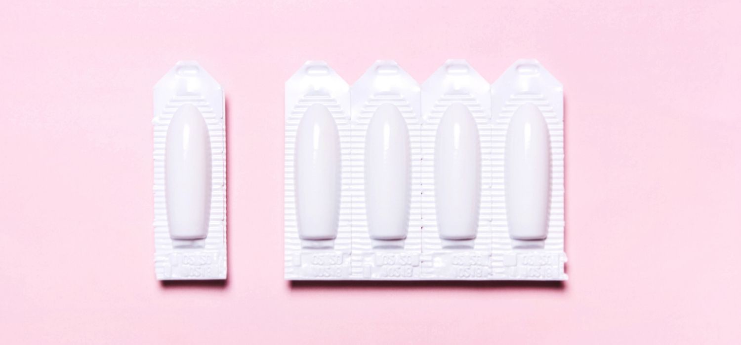 An image of a blister with suppositories on a pink background with one dose detached from the rest of the blister.