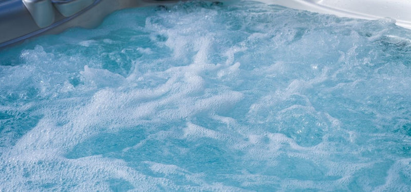 Close-up view of bubbling light-blue water churning inside a hot tub.