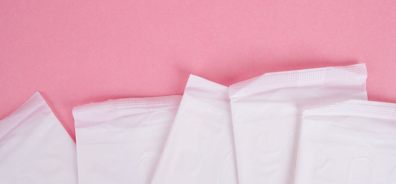 White menstrual pads arranged on a pink background, illustrating vaginal bleeding related to yeast infections.