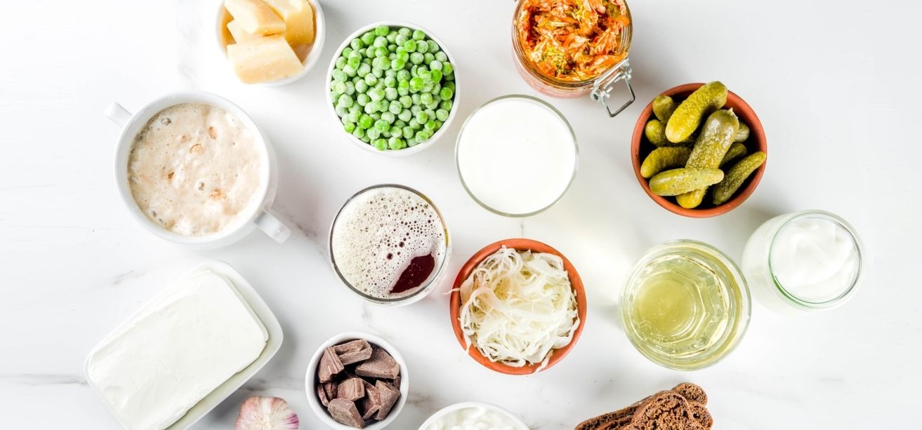 Flat lay of various probiotic and fermented foods in small bowls on a white background.