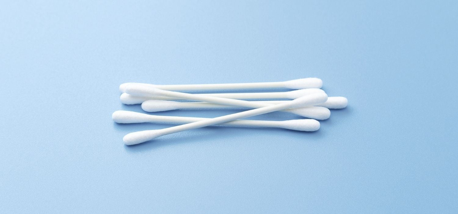 A close up of a bundle of cotton swabs on a light blue background.