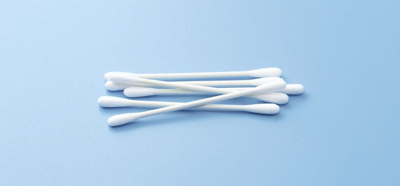 A close up of a bundle of cotton swabs on a light blue background.