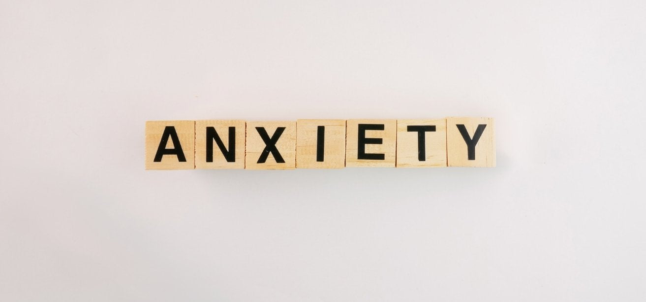 Wooden letter blocks spelling out the word "ANXIETY" centered on a plain white background.