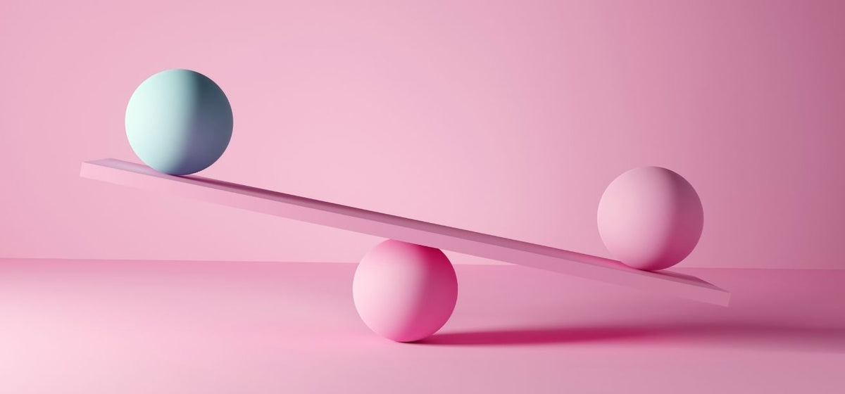 Unbalanced seesaw with a teal sphere and a pink sphere on a pink background, illustrating hormonal imbalance in women.