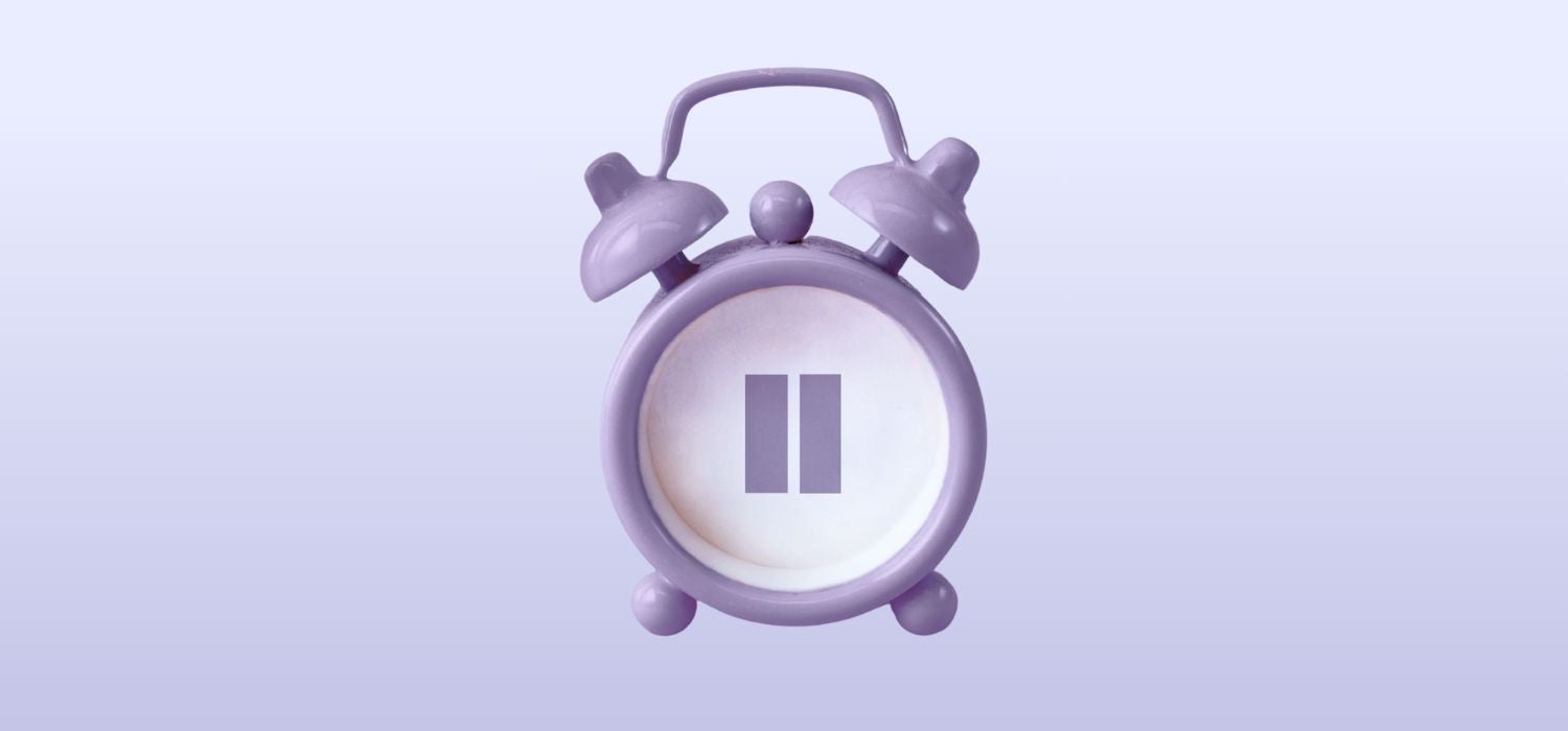 A 3D-style illustration of a purple vintage alarm clock against a light purple background. Instead of a clock face, there is a large purple "pause" symbol in the center.