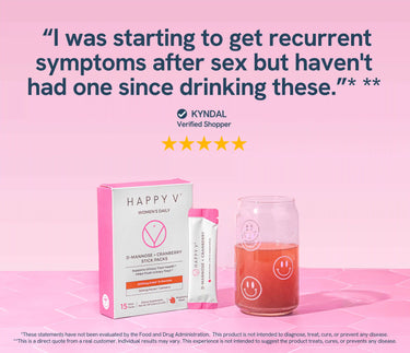 Happy V D-Mannose Cranberry stick pack next to a drink in a glass on a pink background.