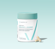 Happy V Debloat + Digest supplement bottle with two capsules on a light background.
