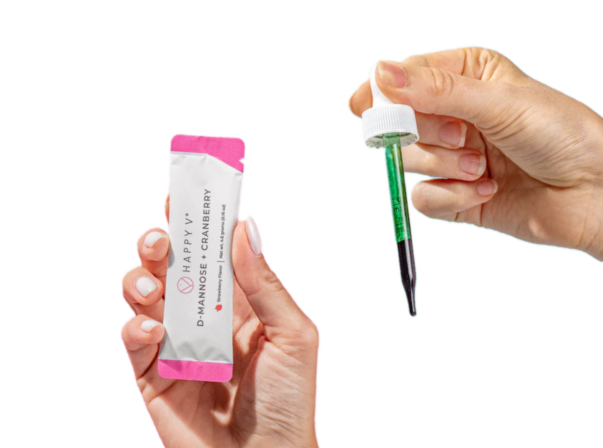 A hand holds a packet of D-Mannose Cranberry and an applicator dropper filled with green liquid.