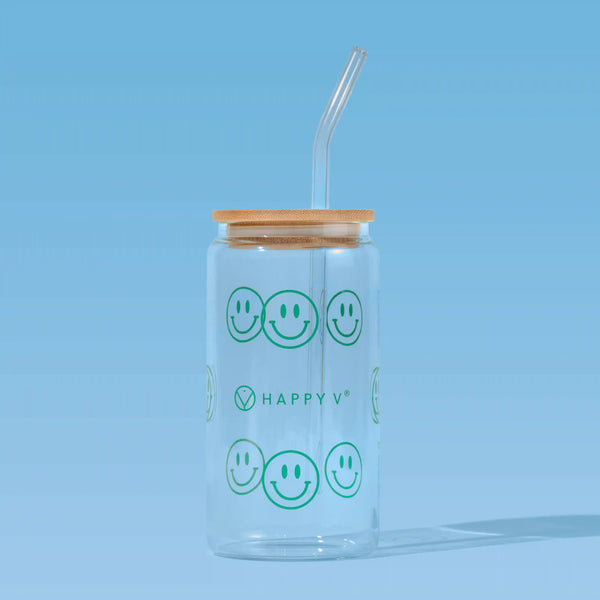 Happy V glass cup with smiley faces and straw on blue background.