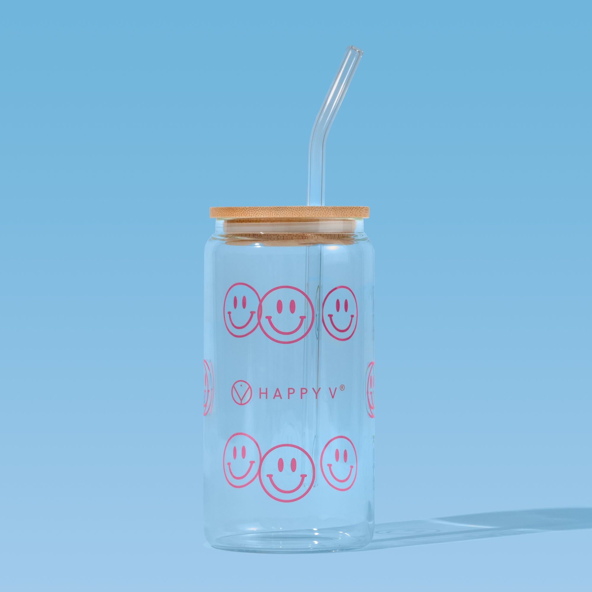 Clear jar with smiley faces and straw beside Happy V supplement bottles on blue background.