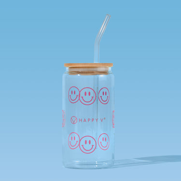 Clear jar with smiley faces and straw beside Happy V supplement bottles on blue background.