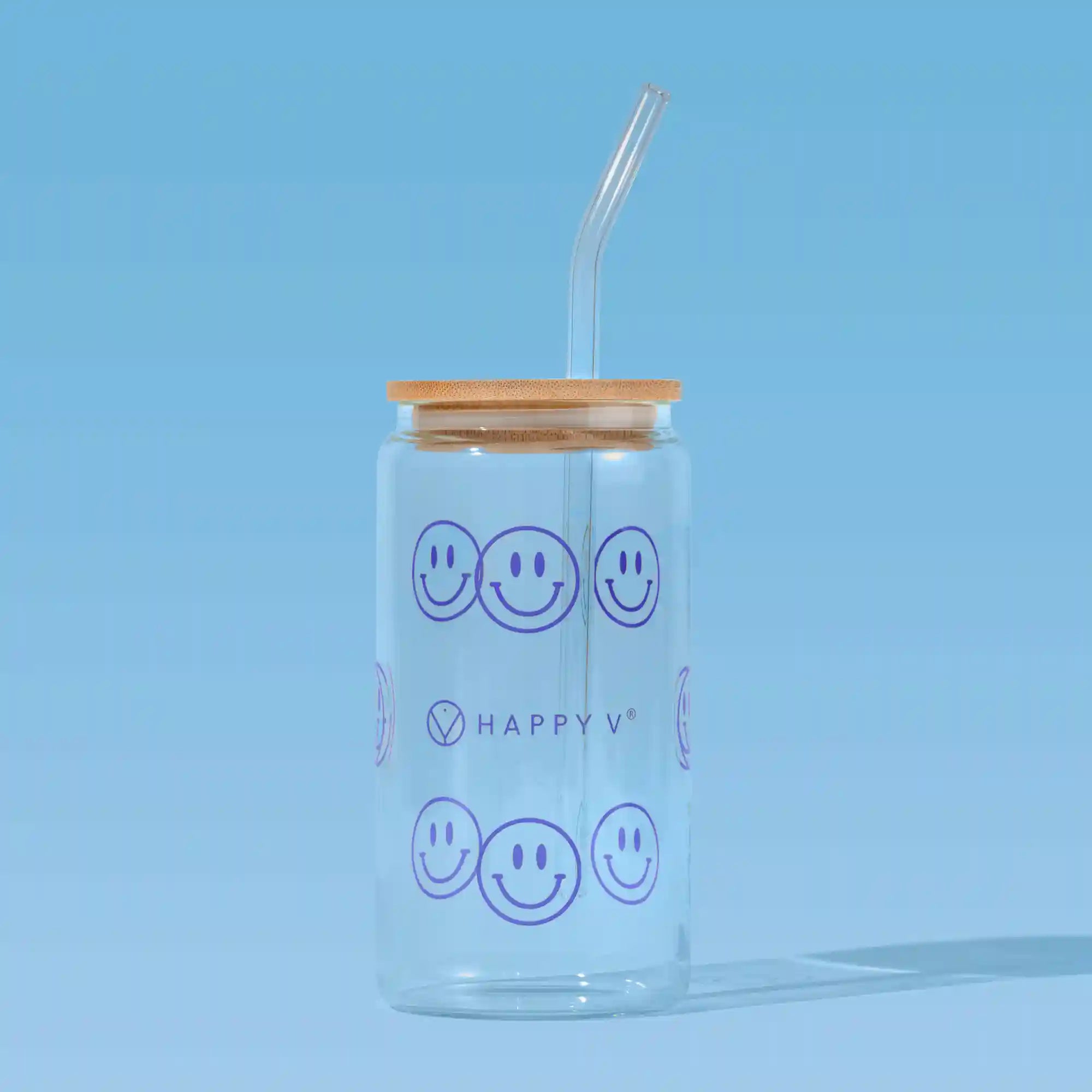 Glass tumbler with smiley faces and a straw, symbolizing Happy V's joyful wellness approach.