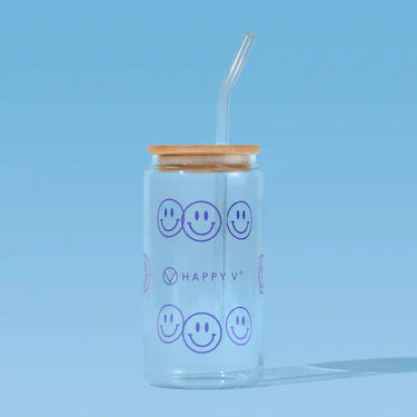 Glass tumbler with smiley faces and a straw, symbolizing Happy V's joyful wellness approach.
