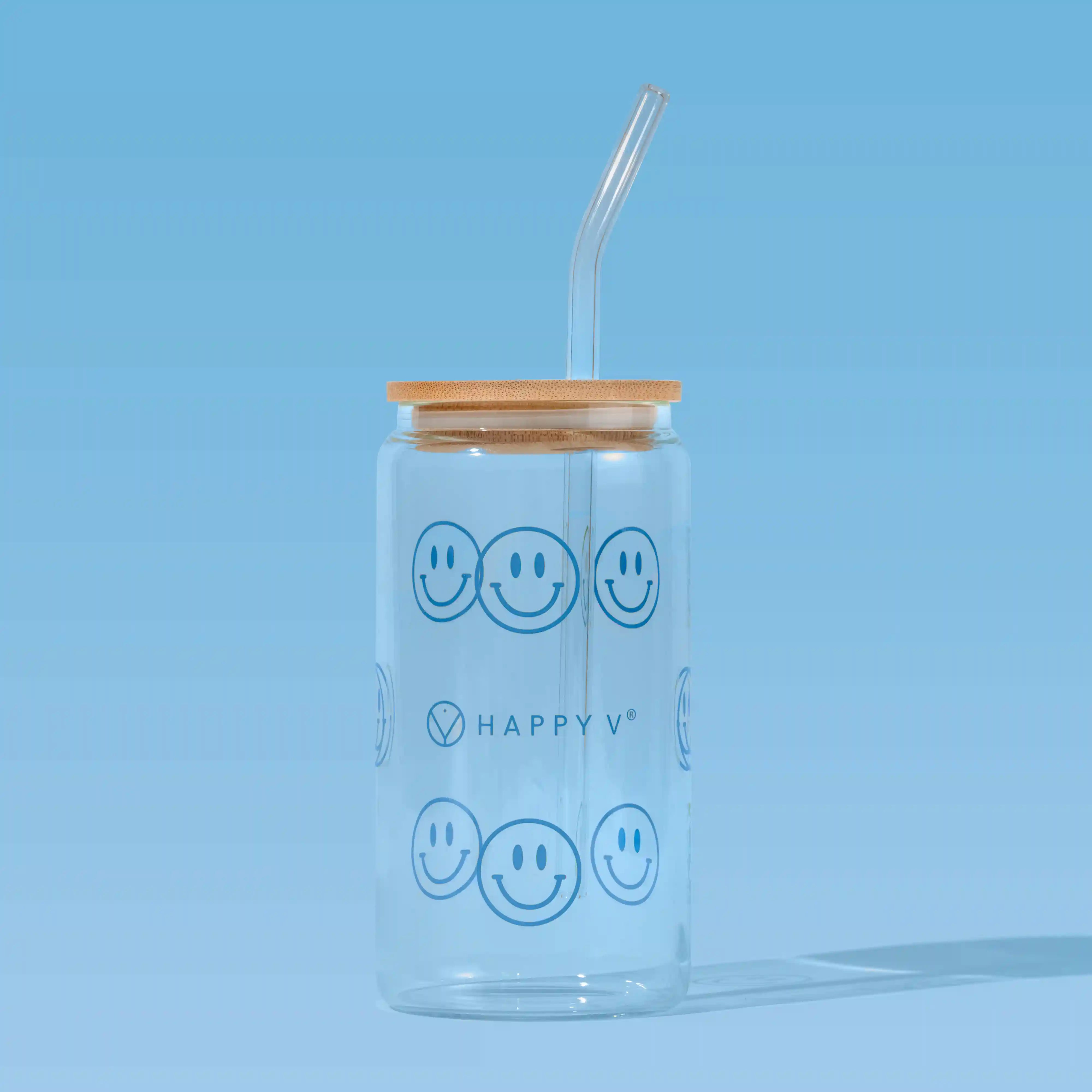 Glass tumbler with smiley faces and a straw, symbolizing Happy V's joyful wellness approach.