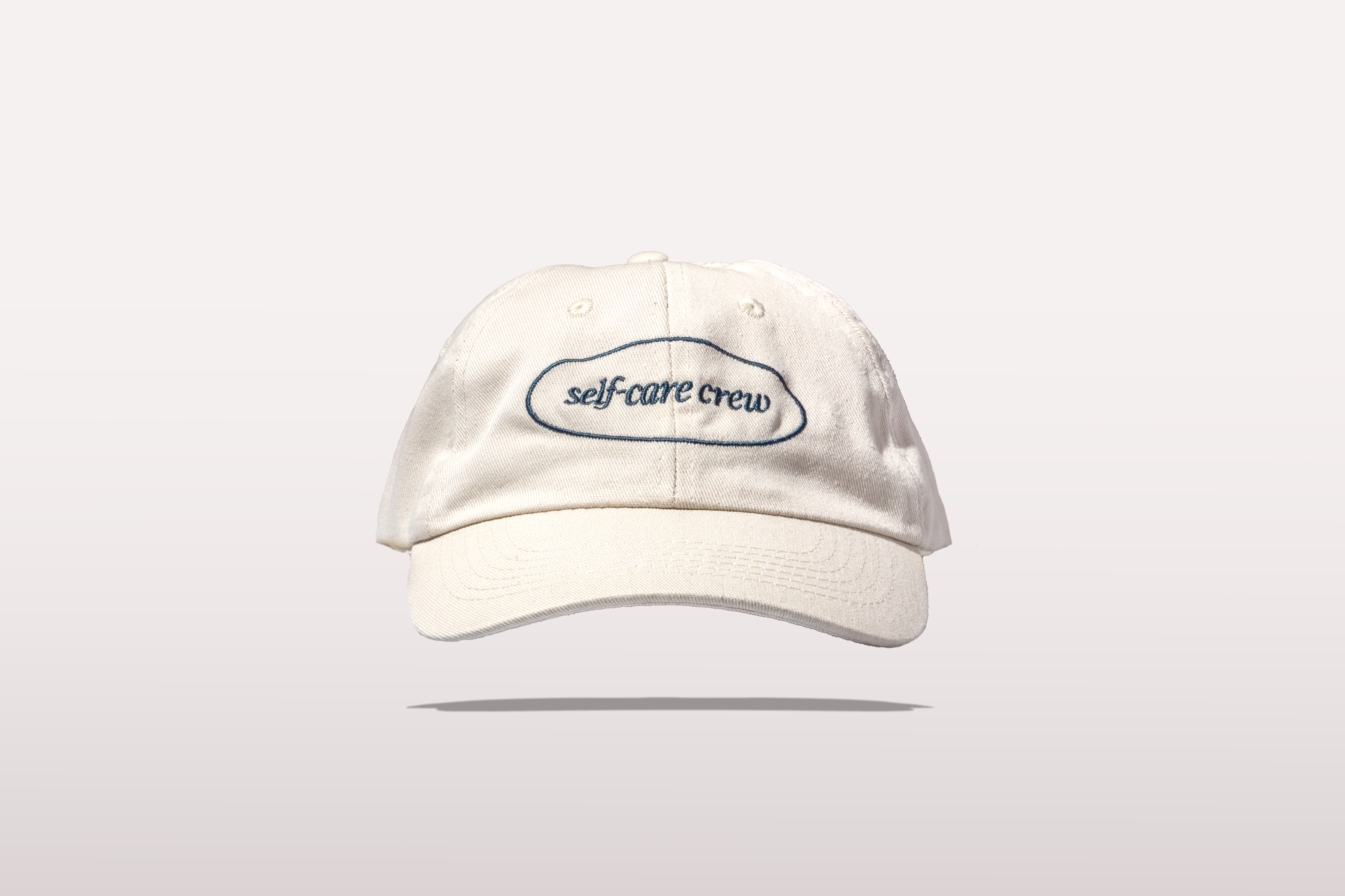 White cap with "self-care crew" text, reflecting Happy V's commitment to women’s wellness.