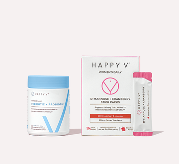 Happy V probiotic bottle alongside D-Mannose + Cranberry stick packs on a wooden surface.