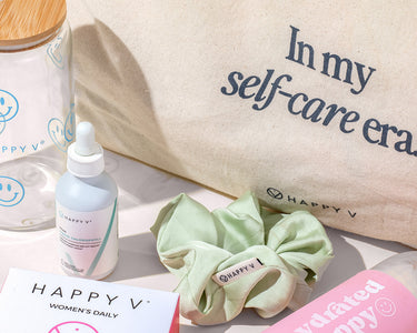 Happy V supplements displayed with a stylish tote bag and a pastel scrunchie.